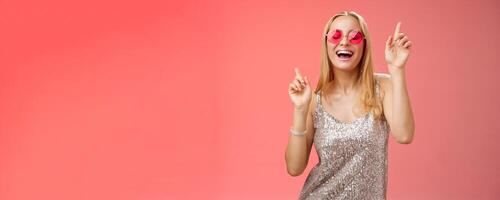 Amused attractive happy smiling woman dancing nightclub having fun enjoying go wild party celebrating b-day wearing stylish dress sunglasses raise index fingers smiling singing along photo