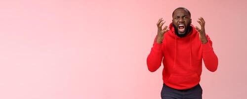 Guy hates subway. Irritated hungry mad bearded african-american man yelling squeez fists frowning grimacing shouting losing temper furiously staring camera go crazy insane, standing pink background photo