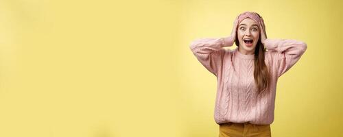 Frustrated girl in panic, screaming grabbing head yelling troubled and scared, staring with buged eyes concerned, feeling nervouse, insecure, shouting frightened and worried against yellow background photo