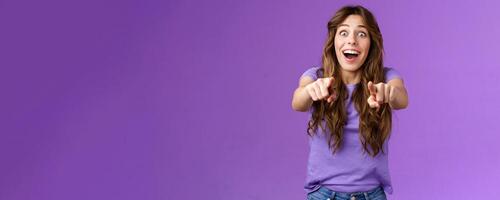 Omg its you. Surprised girl fan cheering joyfully gazing camera popping eyes pointing fingers forward astonished express admiration see superstar wanna receive autograph stand purple background photo