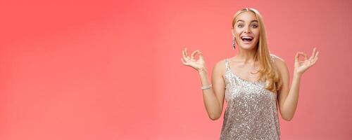 Excited carefree happy stress-free charming blond european woman calm feelings under control show zen gesture standing nirvana lotus pose meditating joyfully smiling, calmd-down red background photo