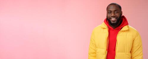 Waist-up happy charismatic good-looking bearded guy in yellow jacket red hoodie smiling joyfully white perfect smile talking have nice friendly conversation, standing pink background photo