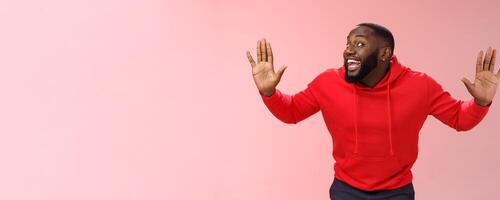 Knock who there. Charming happy funny black bearded guy bending towards camera raised palms move like mime act pressed face glass smiling joyfully fool around playful energized mood photo