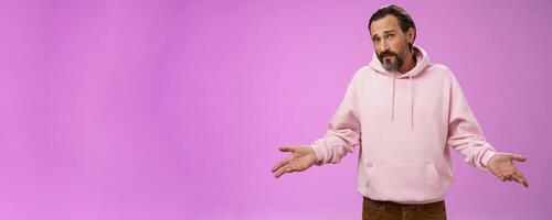 Nothing man could do. Mature bearded guy grey hair 40s spread hands dismay cannot help gesture frowning apologizing shrugging unaware standing perplexed not know anything, purple background photo