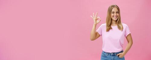 You can count on me. Portrait of confident and assertive young female shop assistant assuring product is great smiling broadly winking at camera and showing okay gesture in like and approval photo