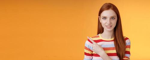 Curious smart female redhead coworker asking friend who was that pointing left index finger look camera thoughtful questioned wanna know answer smiling intrigued standing orange background photo