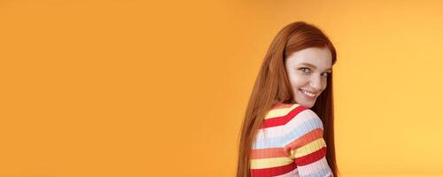 Tenderness, romance, seduction concept. Attractive cheeky flirty young redhead daring girl turn behind look shoulder camera smiling silly coquettish giggle express sympathy affection photo