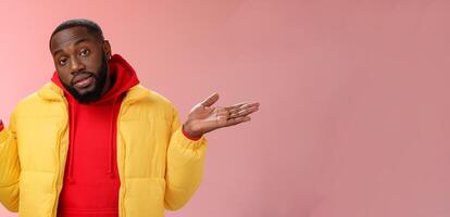 Indoor shot black bearded 25s guy shrugging hands raised sideways dismay clueless gesture have no idea standing careless questioned unaware what happened unbothered pink background photo