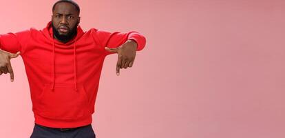 Questioned displeased pissed handsome serious-looking athletic black guy bearded frowning look perplexed wondered freak out pointing down waiting explanation, standing frustrated pink background photo