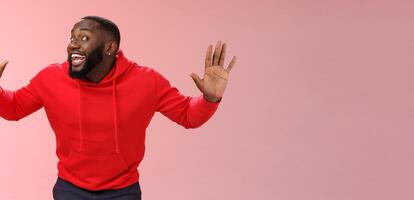 Knock who there. Charming happy funny black bearded guy bending towards camera raised palms move like mime act pressed face glass smiling joyfully fool around playful energized mood photo