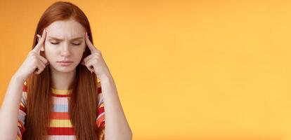 Girl getting thoughts piled trying think stright focusing concentrating important task remember number touch temples close eyes look seriously standing puzzled suffer headache, orange background photo