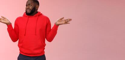 African american man cringe shake head unaware frowning grimacing aversion dislike shrugging hands raised sideways have no idea, standing dissatisfied unpleasant question, clueless pink background photo