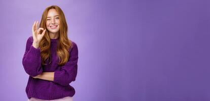 Nice work you did great. Satisfied and happy charming assertive and supportive redhead woman in purple sweater smiling and winking in approval showing okay gesture, liking product over violet wall photo