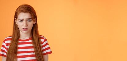 Close-up stupified puzzled redhead perplexed woman, open mouth raise eyebrow full disbelief, confused frowning, cannot understand person saying nonsense, stand questioned orange background photo