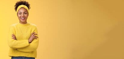 Serious powerful good-looking smiling african-american female femenist blogger cross hands chest confident pose grinning delighted enjoying watching working process, standing yellow background photo