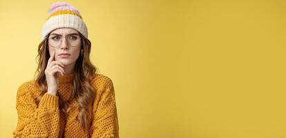 Serious-looking complicated attractive smart girl solving issue mind look disturbed perplexed aside touching face frowning thoughtful, doubting suspicious feeling, standing unsure yellow background photo