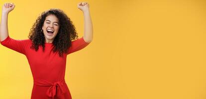 Oh yeah I am winner, on top of world. Excited ambitious and happy young successful busiensswoman getting promotion yelling yes with broad smile and closed eyes lifting hands in triumph and celebration photo