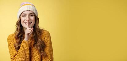 Shush listen. Portrait attractive flirty smiling devious cute european woman have secret showing shh gesture index finger pressed lips sharing interesting rumor, standing happily yellow background photo