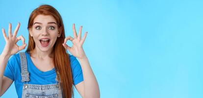 Excellent choice. Redhead female friend approve awesome idea, support accept good purshace, show okay ok confirmation gesture, smiling judging, give positive feedback, stand satisfied blue background photo