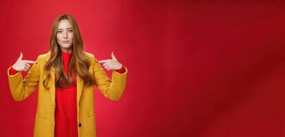 Self-assured assertive and optimsitic charming female entrepreneur with ginger hair in yellow coat pointing at herself proudly brag own success or willing to be candidate smiling confident photo