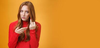 Redhead girl asking where wedding ring being fed up waiting proposal extending finger and pointing at it questioned and pissed having argument with boyfriend over orange background photo