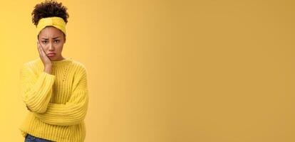 Upset cute gloomy young timid girl offended feel sadness regret touch cheek painful toothache make upset miserable pitty expression, troubled uncertain what do standing insecure yellow background photo
