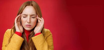 Girl trying keep thoughts together feeling tensed and pressured close eyes frowning rubbing temples, feeling headache or migraine, focusing on thoughts over red background photo