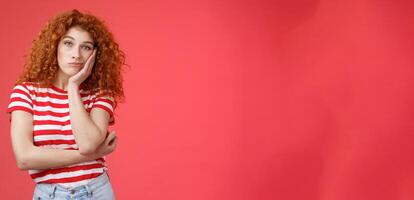 Playful redhead gorgeous girl feel sad lacking energizing party lean palm look indifferent express boredom lonely feelings attend boring meeting standing upset reluctant red background photo