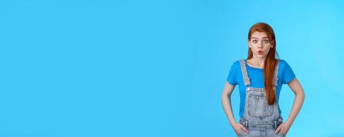 Worried nervous cute redhead female feel anxious pressured before important interview, hold breath, exhale, pouting difficult concerning situation, look insecure stand blue background photo