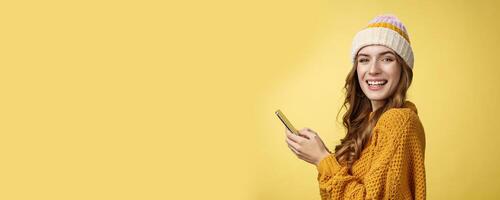 Profile shot entertained charming young woman playing mobile phone holding smartphone turning camera delighted having fun using cool app editing pics travel blogger messaging posting online photo