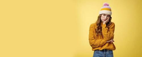 Bored annoyed fed up cute girlfriend cannot stand boring talks leaning palm indifferent look camera under forehead uninterested not paying attention, standing bothered yellow background photo