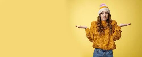 How should I know. Portrait confused perplexed worried cute female assistant shrugging spread hands sideways clueless unaware cannot understand what happened unsure, unaware yellow background photo