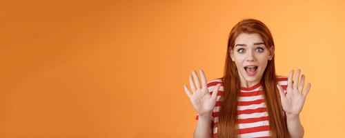 Shocked inssecure worried redhead woman plead not guilty, trying calm down angry customer, raise hands surrender innocent, open mouth, stare concerned camera, defend herself, explain situation photo