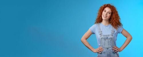 Cheerful motivated accomplished attractive redhead curly-haired ginger girl hold hands waist confident pose assertive own power tilt head smiling delighted self-assured, inspired create photo