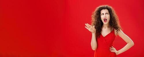 Stop talking you making me sick. Displeased and arrogant picky dark-haired woman with curly hairstyle saying blah-blah turning away from annoying person rolling eyes up and frowning from aversion photo
