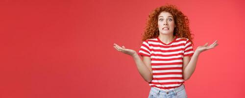 Yikes how should I know. Unaware worried awkward cute redhead curly girl clench teeth smirking uncertain panic cannot answer popping eyes confused shrugging hands spread sideways full disbelief photo