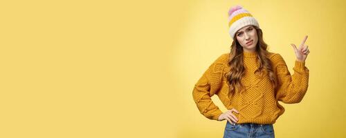 You call it advertisement, bad. Unimpressed displeased snobbish demanding female displeased hotel service pointing upper right corner cringing bothered frowning complaining yellow background photo