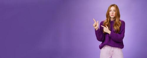 Upset and gloomy woman in sorrow feeling regret of missing huge sales looking reckelss and unhappy pointing questioned at upper left corner with hopeless expression over purple background photo