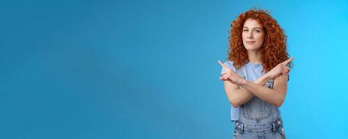 Curious creative redhead attractive modern young curly-haired female look intrigued pointing sideways left right squinting camera asking advice making choice deciding which product blue background photo