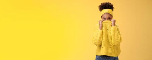 Cute upset scared timid insecure african-american offended girl hiding face pulling sweater collar nose frowning pouting look sorrow insulted afraid watching scary horror movie alone, need support photo