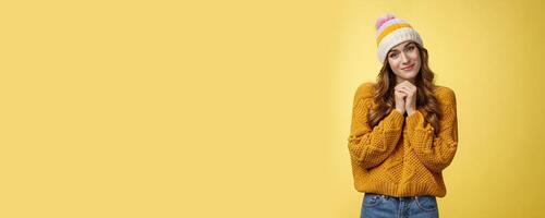 Touched charming cute silly young girl make flirty gazes camera press palms together checking out something moving cute, tilting head seeing adorable kitten, smiling delighted yellow background photo
