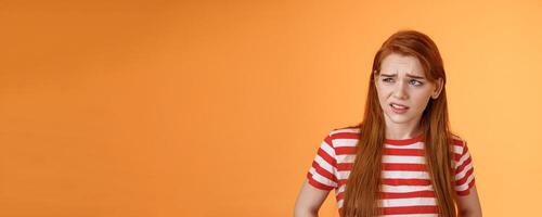 Close-up unsure redhead teenager frowning uncertain, having doubts, look perplexed left side copy space, hesitating, cringe dislike and disappointment, stare frustrated, uneasy decision photo
