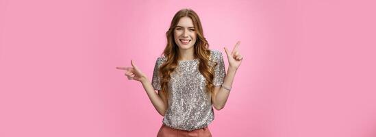 Pretty confident carefree caucasian woman enjoying party pointing sideways different sides smiling unbothered happy show you choices, opportunities, make decision standing pink background photo