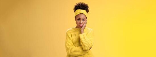 Upset cute gloomy young timid girl offended feel sadness regret touch cheek painful toothache make upset miserable pitty expression, troubled uncertain what do standing insecure yellow background photo