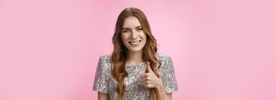 Nice choice, support you. Pleased friendly-looking attractive young caucasian girl show thumb-up cheerfully smiling like your idea, enjoying cool party, express approval, agree, recommending product photo