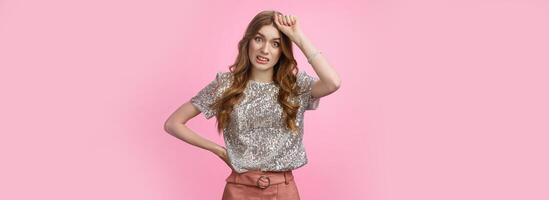 Forgetful silly attractive young european female punching herself head grimacing forgot important meeting messed up time, standing awkward bothered pink background look displeased camera photo