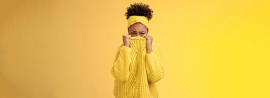 Cute upset scared timid insecure african-american offended girl hiding face pulling sweater collar nose frowning pouting look sorrow insulted afraid watching scary horror movie alone, need support photo