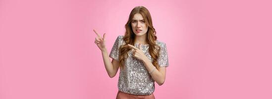 Unsure reluctant attractive glamour caucasian girl asking question doubtful pointing upper right corner lost seeking address party, grimacing cringe hesitant, standing uncertainpink background photo