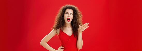 Stop talking you making me sick. Displeased and arrogant picky dark-haired woman with curly hairstyle saying blah-blah turning away from annoying person rolling eyes up and frowning from aversion photo