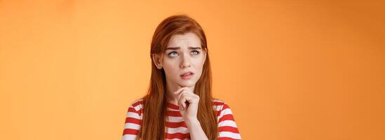 Perplexed redhead woman trying make calculations mind, frowning focused, look up puzzled thoughtful, touch chin, thinking, pondering important decision, make choice, solve problem photo